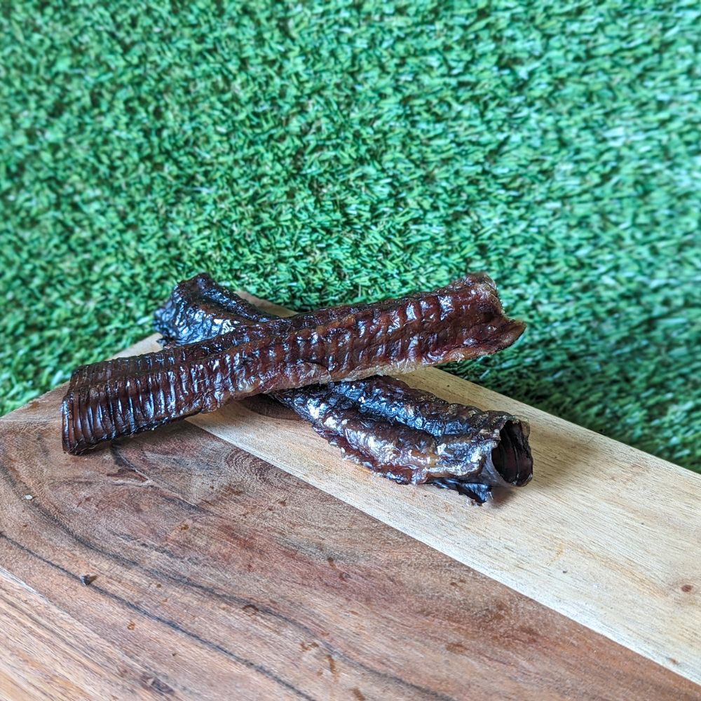 Emu trachea dog treat on wooden board placed on grass Bonza Dog Treats