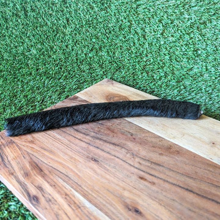 XLarge hairy beef hide scroll on wooden board laying on grass Bonza Dog Treats